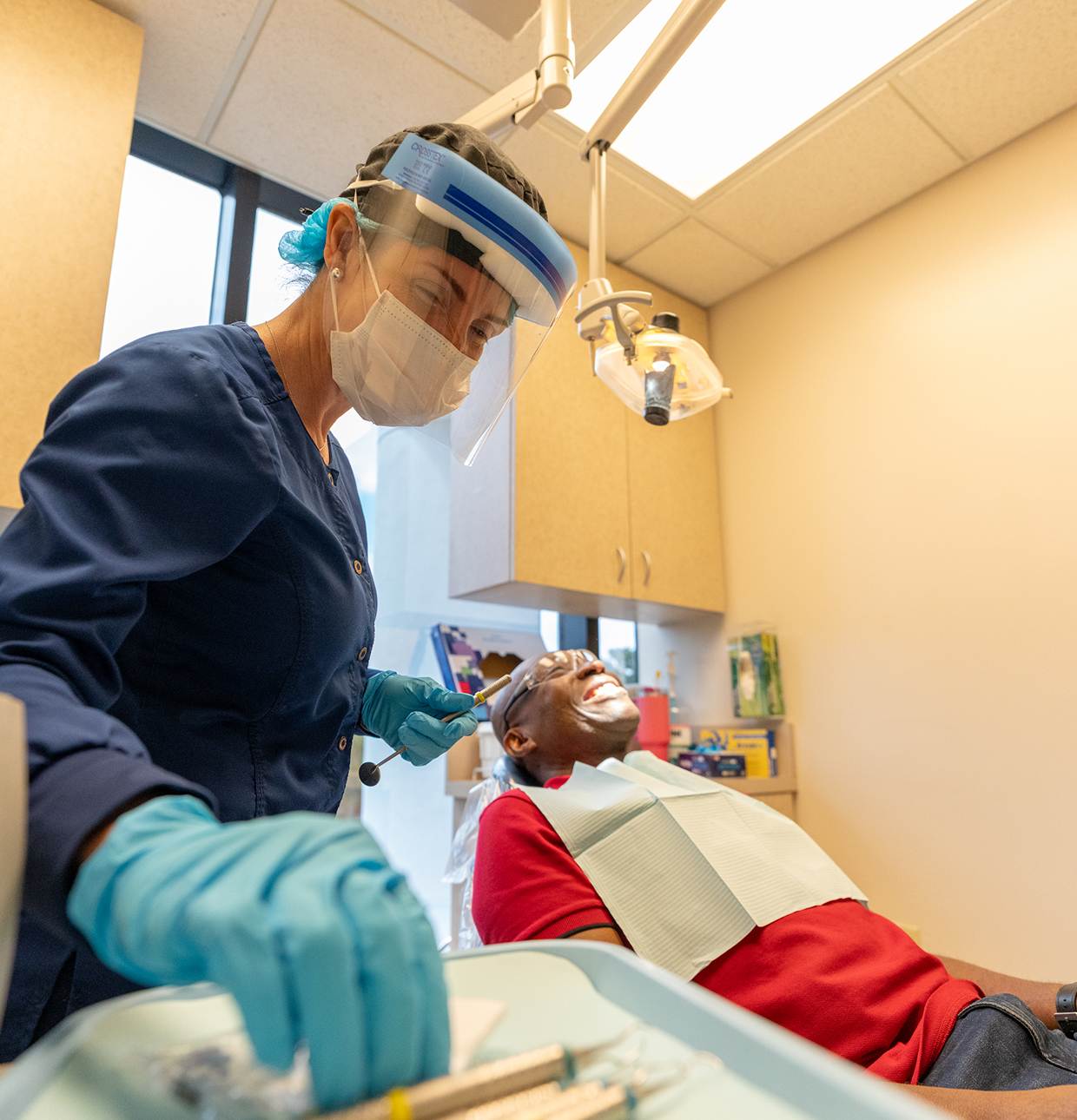 Dental professional in PPE assisting patient during dental treatment, highlighting advanced care and patient-focused environment at Center for Dental Implants.